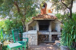 a stone oven in a yard with a green chair at Apartments Ante in Mandre