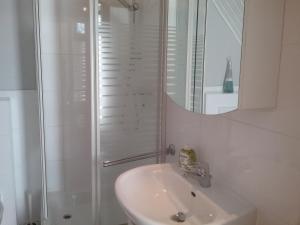 a white bathroom with a sink and a shower at Altstadt-Apartment Petershagen in Petershagen +13 photos