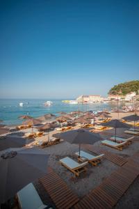 a beach with chairs and umbrellas and the ocean at Hotel Riva by Aycon in Petrovac na Moru
