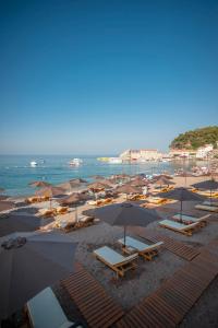 a beach filled with lots of beach chairs and umbrellas at Hotel Riva by Aycon in Petrovac na Moru