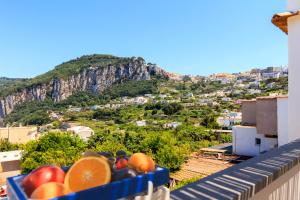 eine Schale Obst auf einem Balkon mit einem Berg in der Unterkunft AQUAMARINE Relaxing Capri Suites in Capri