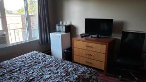 a bedroom with a bed and a television on a dresser at Belmont Inn in Sudbury