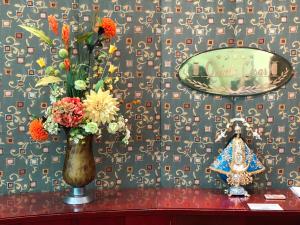 un jarrón de flores sobre una mesa con una pared en Hotel Quinta Cesar en San Juan de los Lagos