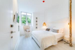 a white bedroom with a bed and a chair at Garam Lisboa in Lisbon