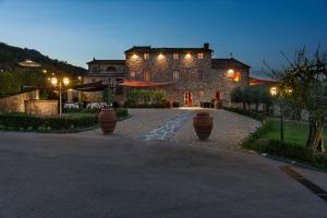 ein großes Steinhaus mit Lichtern an einer Auffahrt in der Unterkunft Hotel Villa Volpi in Lucca