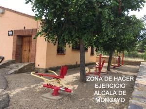 a group of red chairs sitting next to a tree at Casa Rural La Tejada in Alcalá de Moncayo