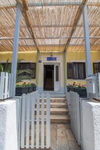 a building with a fence and a building with a ceiling at Hostel Flora in Mali Lošinj