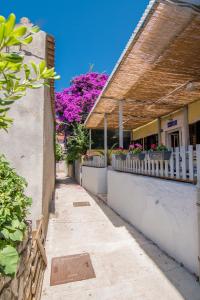 an alley with a white fence and purple flowers at Hostel Flora in Mali Lošinj
