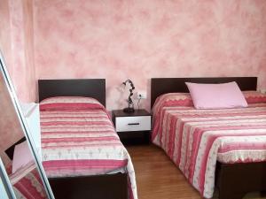 two beds in a bedroom with pink walls at B&B dei Laghi in Brebbia
