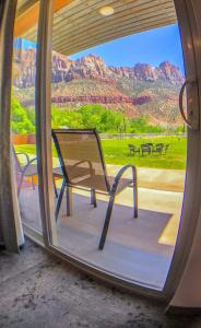 une chaise assise sur une terrasse couverte avec vue sur les montagnes dans l'établissement Bumbleberry Inn, à Springdale