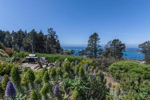 a garden with purple flowers and the ocean in the background at Cottages at Little River Cove in Little River