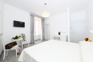 a white bedroom with a bed and a table at Palazzo Gargano Amalfi in Amalfi
