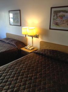 a hotel room with two beds and a lamp on a table at Coeur D' Alene Budget Saver Motel in Coeur d'Alene