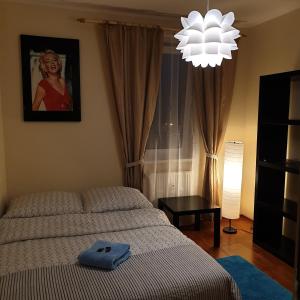 a bedroom with a bed and a chandelier at Apartament Sloneczny Taras in Olsztyn