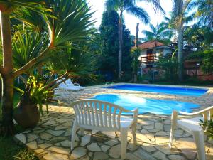 uma piscina com duas cadeiras e uma mesa e um banco em Pousada Brasil Paraty em Paraty