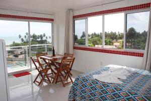 a bedroom with a bed and a table and windows at Flat com Varanda e Vista Mar in Paracuru