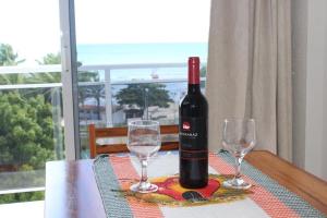 a bottle of wine sitting on a table with two glasses at Flat com Varanda e Vista Mar in Paracuru