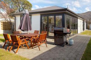 a patio with a table and chairs and a grill at Pembroke Villa in Wanaka