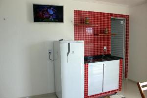 una nevera blanca en una cocina con azulejos rojos en Flat com Varanda e Vista Mar, en Paracuru