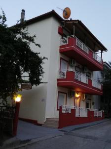 a red and white building with a balcony at Grande Apartments in Limenaria
