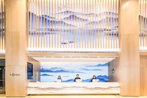 um lobby com três pessoas sentadas em seus computadores em Atour Hotel Weifang Jinma Road City Hall em Weifang