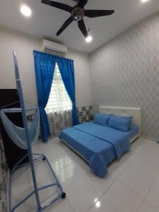 a bedroom with a blue bed and a ceiling fan at Selesa Indah Guest House Melaka - Near City Centre in Melaka