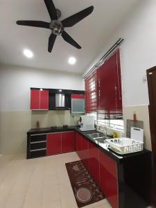 a kitchen with red cabinets and a ceiling fan at Selesa Indah Guest House Melaka - Near City Centre in Melaka