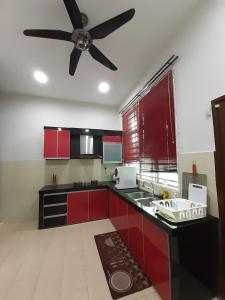 a kitchen with red cabinets and a ceiling fan at Homestay Fully Aircond Free Wifi Near MITC,UTEM in Malacca