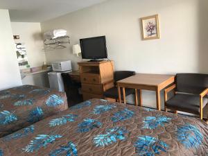 a hotel room with a bed and a desk with a tv at Lazy U Motel in Rapid City