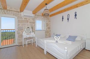 a white bedroom with a bed and a desk at Villa Sea star in Babino Polje