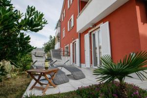 eine Terrasse mit Stühlen und einem Tisch neben einem Gebäude in der Unterkunft Apartment Sally in Čižići + 14 Fotos