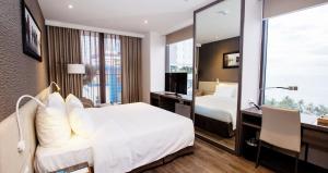 a hotel room with a bed and a desk and a mirror at Alana Nha Trang Beach Hotel in Nha Trang
