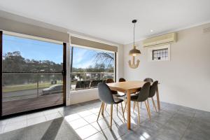 a dining room with a table and chairs and a window at Hybiscus Waterfront Apartments in Lakes Entrance