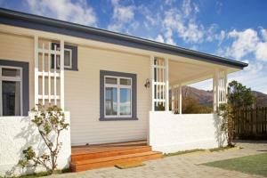 a small white house with a wooden porch at McDougall Cottage in Wanaka