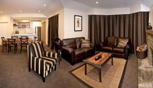 a living room with leather furniture and a table at Pembroke Lodge in Wanaka
