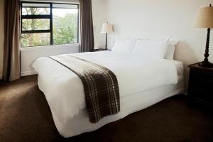 a bedroom with a large white bed with a window at Pembroke Lodge in Wanaka