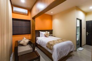 ein Schlafzimmer mit orangefarbenen Wänden, einem Bett und einem Fenster in der Unterkunft AB Hotel Kuta in Kuta