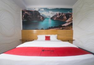 Un dormitorio con una cama grande con un cuadro en la pared. en RedDoorz Plus Syariah @ Pentadio Gorontalo, en Gorontalo