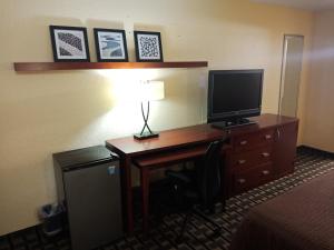 Habitación de hotel con escritorio, TV y lámpara. en Budget Inn Of Orlando en Orlando