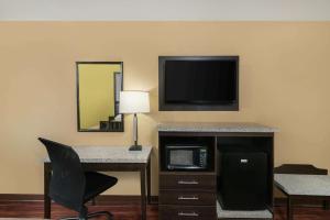 a hotel room with a desk with a computer and a tv at Super 8 by Wyndham Raleigh North East in Raleigh