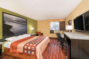 een hotelkamer met een bed en een flatscreen-tv bij Super 8 by Wyndham Raleigh North East in Raleigh