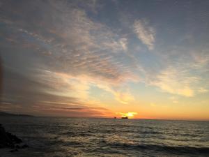- un coucher de soleil sur l'océan avec un bateau au loin dans l'établissement Playa Miramar, à Viña del Mar