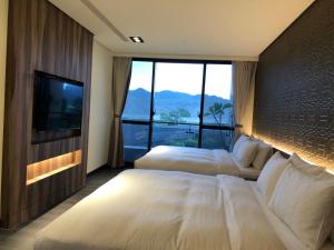 a hotel room with two beds and a television at Tan Villa in Taitung City