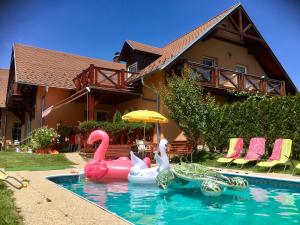 a swimming pool with swans and ducks in front of a house at Apartments Lipno Serafin in Lipno nad Vltavou