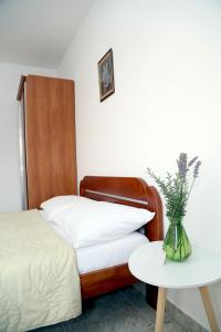 Un dormitorio con una cama y una mesa con un jarrón de flores en Apartments Ardura, en Petrovac na Moru