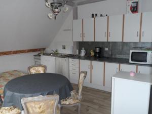 uma cozinha com armários brancos e uma mesa e cadeiras em CHEZ LE VIGNERON em Westhalten