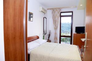 - une chambre avec un lit, une télévision et une fenêtre dans l'établissement Apartments Ardura, à Petrovac na Moru