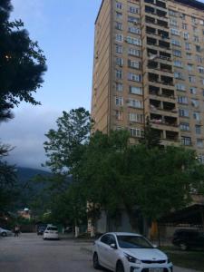 a white car parked in front of a tall building at Apartment in Gagra in Gagra