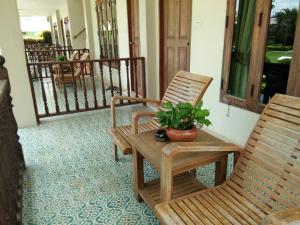 a porch with two rocking chairs and a potted plant at Scent of Sukhothai Resort in Sukhothai