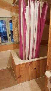a bath tub with pink and white curtains in a bathroom at Holiday Country Villa with Panoramic Views in Bouteilles-Saint-Sébastien